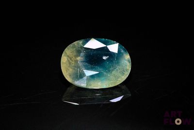 a close up of a blue and green gemstone on a black surface