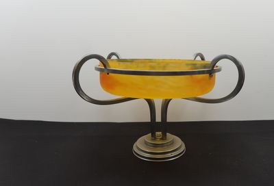 an image of a yellow glass vase with two handles on a black table