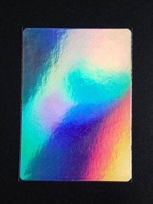 a close up of the back side of a rainbow colored notebook on a black surface