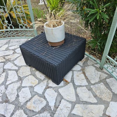 une plante en pot posée sur une caisse en osier, sur une terrasse
