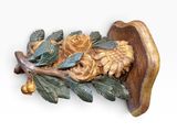 a wooden carving of a bird with leaves and flowers on it