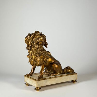 une statue antique en bronze représentant un lion, posée sur un socle en marbre