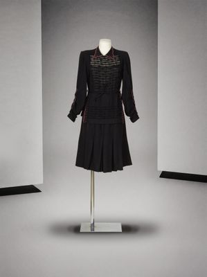 une robe noire posée sur un mannequin dans une pièce blanche