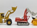 three toy construction vehicles that are on a white surface