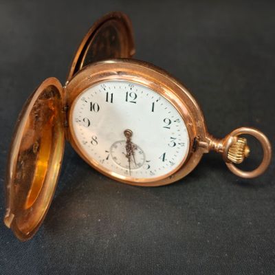 une montre de poche en or posée sur une surface noire