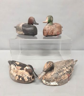 trois canards en bois sont posés sur une vitrine transparente