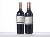 two bottles of red wine sitting on top of a white table