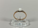 a ring with a pearl on top of a clear stand