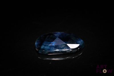 a close up of a blue sapphire stone on a black surface