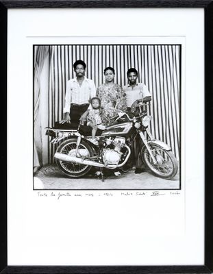 a black and white photo of a man and two women and a motorcycle