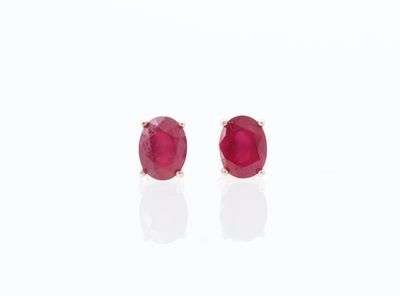 une paire de boucles d'oreilles à clous ornées de rubis, posées sur un fond blanc