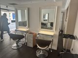 une photo d'un salon de coiffure avec des fauteuils et des miroirs