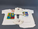 trois t-shirts et une casquette sont posés sur une table