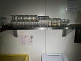 des bouteilles et des verres posés sur une étagère au-dessus des toilettes dans une salle de bains