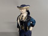 une figurine représentant un homme portant un chapeau et une veste