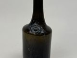 une bouteille en verre brun avec un bouchon noir posée sur une surface blanche