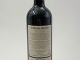 a bottle of red wine sitting on top of a white table