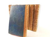 several old books stacked on top of each other on a white surface