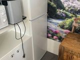 a refrigerator and microwave in a small room with a mural on the wall