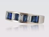 a close up of a white gold ring with blue sapphires and diamonds