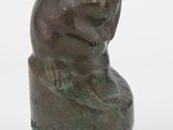 sculpture en bronze représentant un ours assis sur un rocher, sur fond blanc