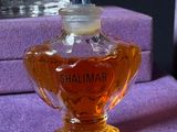 a small bottle of perfume sitting on a purple table