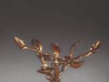 an antique bronze figurine of a deer holding a branch of a tree