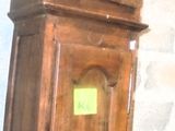une femme debout à côté d'une horloge de parquet dans une pièce