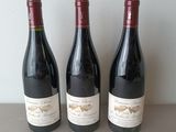 three bottles of wine sit on a table next to each other