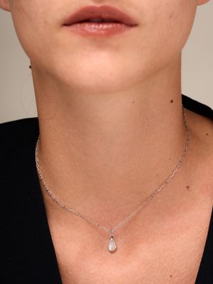 une femme portant un t-shirt noir et un collier en argent orné d'un pendentif en forme de larme