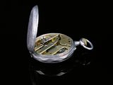 a close up of a pocket watch on a black surface