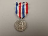 silver medal with red, white, and blue ribbon on a white table