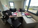 a desk with two computer monitors and a chair in front of a window