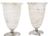 une paire de vases en marbre blanc posés sur un socle en métal