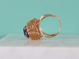 a close up of a gold ring with a purple stone in it