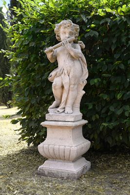 a statue of a boy playing a flute in a garden