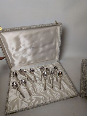 silverware in a silver case sitting on a table next to a vase