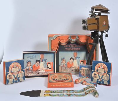un appareil photo et quelques photos posés sur une table à côté d'un projecteur de cinéma