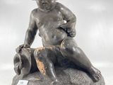 une vieille statue représentant un garçon assis sur un rocher
