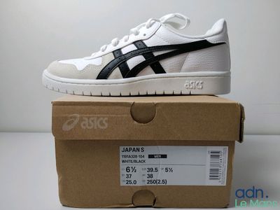 La boîte contient une paire de baskets blanches et noires.