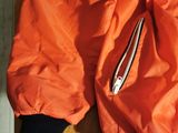 an orange jacket sitting on top of a wooden table next to a pair of scissors
