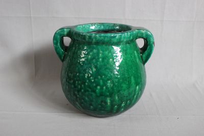 un vase vert posé sur une surface blanche