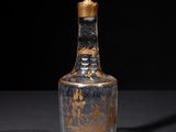 an old glass bottle with a gold lid sitting on top of a table
