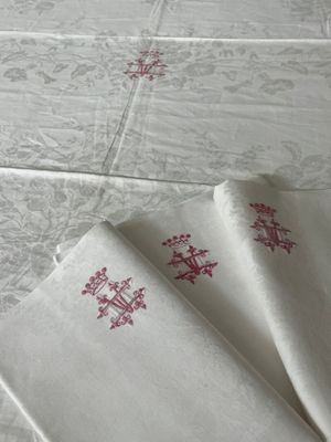trois serviettes blanches ornées de motifs brodés rouges, posées sur une table