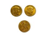 Trois pièces d'or sont représentées sur une surface blanche