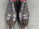 pair of men ' s leather shoes with red soles on a gray surface