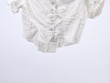 shirt hanging on a hanger in a white room with a white wall