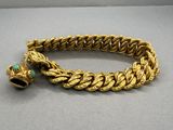 a close up of a gold bracelet with a bell on it