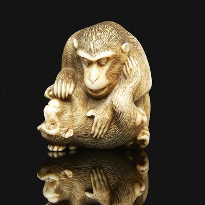 an ivory nets sculpture of a monkey holding a baby monkey