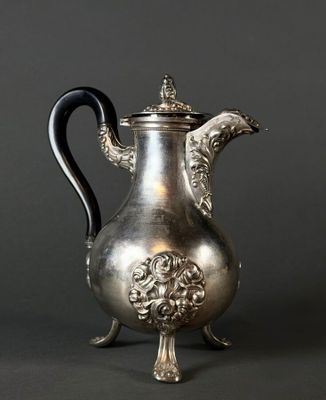 une cafetière ancienne en argent avec une poignée noire sur fond gris